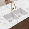 Forio 813 matt white double bowl quartz sink undermounted in a marble benchtop with a brass pull-out mixer