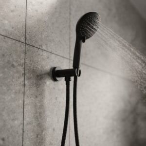 Coen 3 function shower on bracket in black installed on a tiled shower wall